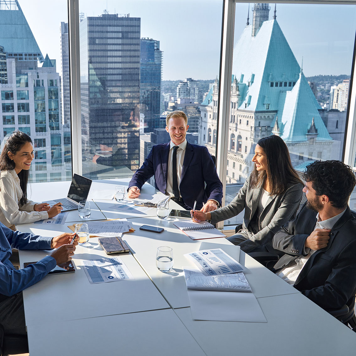 Executive leadership team meeting around a conference table in a high-rise office